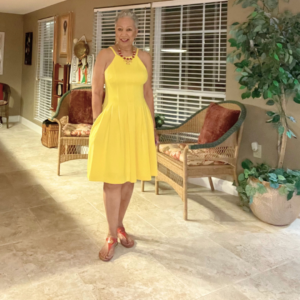 Reslience is the ability to overcome obstacles. Picture of Diane Givens standing in a yellow sun dress.