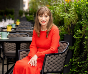 Midlife and menopause advocate Rachel  Lankester pictures sitting in a garden in a red dress