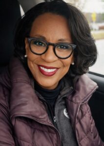 Reinvention at 65! Lillian Taylor has a story to tell that's full of courage and possibility. She's pictured smiling into the camera wearing a purple vest.